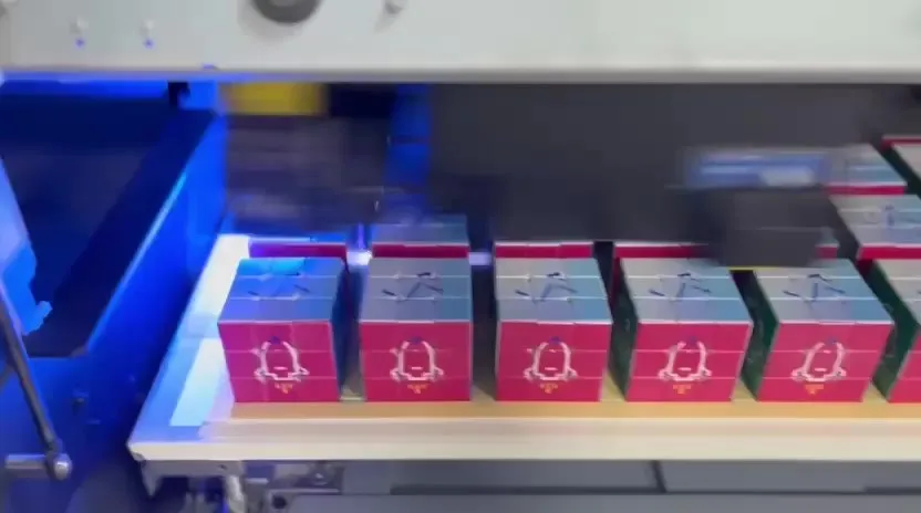 Branded Rubik’s cubes lined up under the UV print head